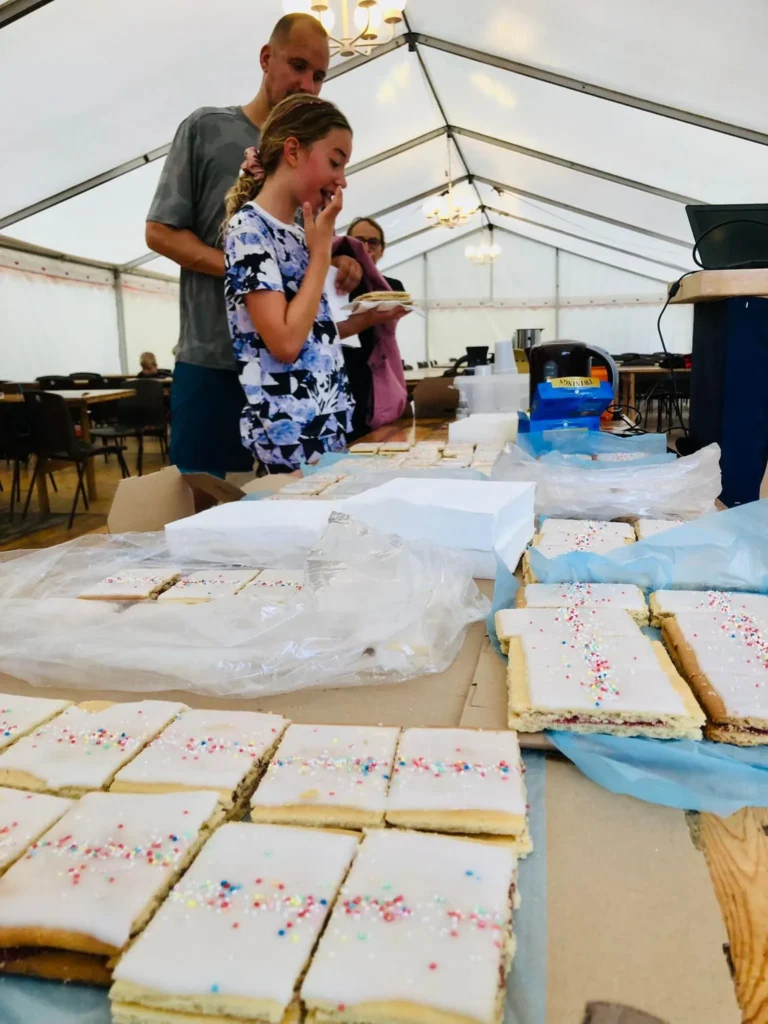 Hindbærsnitter med lyserød glasur og krymmel på borde, klar til servering efter Hindbærsnitteløbet i Hobro.