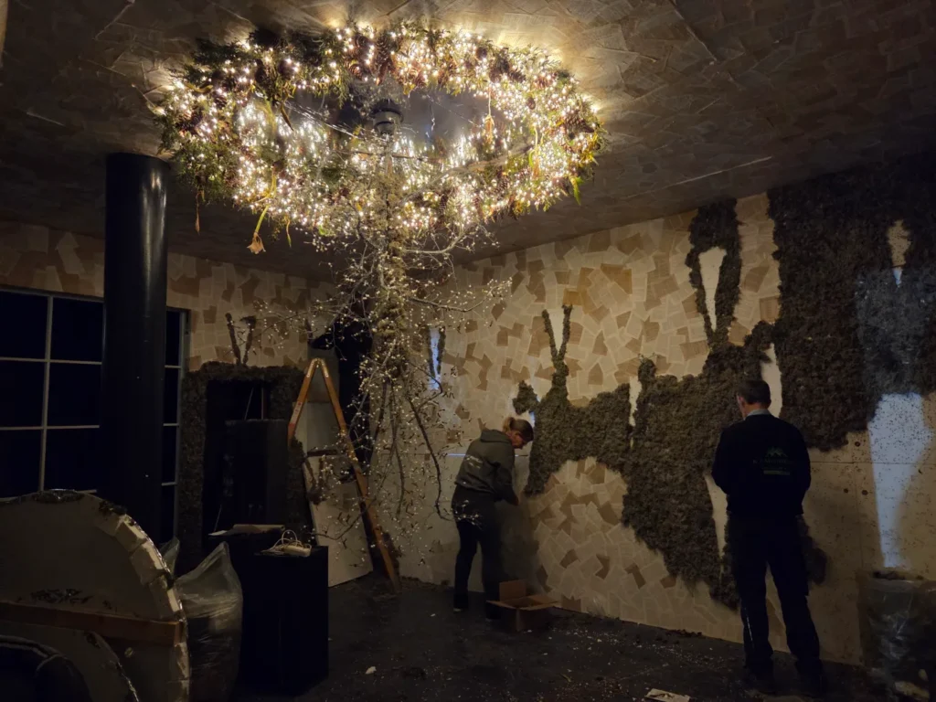 I rummet med den store mistelten er der snart kun selve misteltenen tilbage. Her fjernes dekorationer og lav fra vaeggene der bestaar af flamingoplader med paaklistrede sider fra gamle boeger